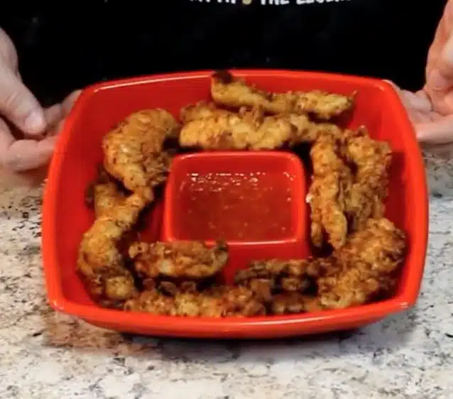 Marinated Chicken fingers in red dish with sauce