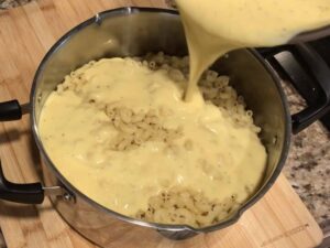 Pouring cheese sauce of elbow macaroni