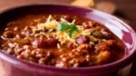 Burgundy bowl of chili with cheese on top