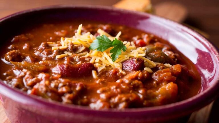 Burgundy bowl of chili with cheese on top