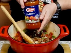 Adding pasta sauce to pot of goulash